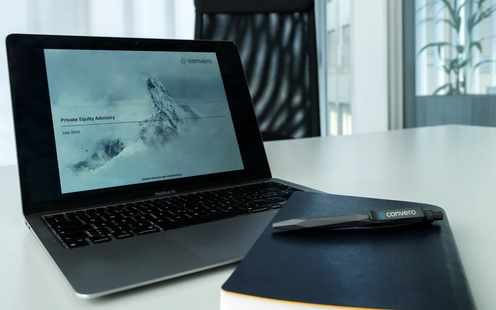 Laptop displaying a Convero presentation beside a branded notebook and pen